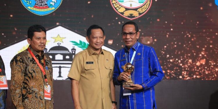 Pj. Bupati Buton, Drs. Basiran, MSi bersama Menteri Dalam Negeri Tito Karnavian saat menerima UHC Award dari BPJS Kesehatan.